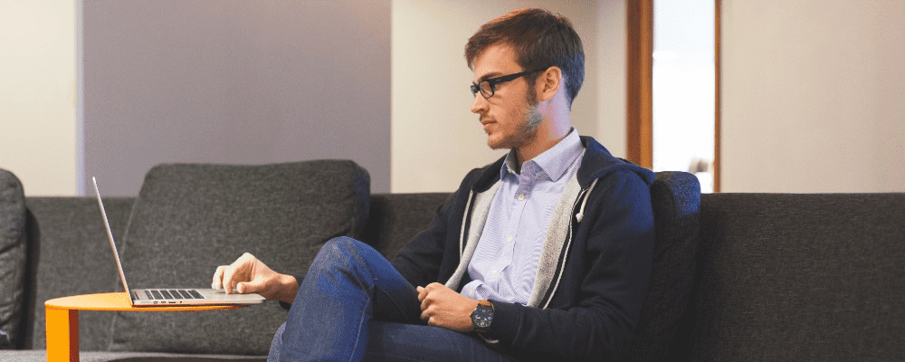 Mand låner penge på sin computer hjemme fra sofaen